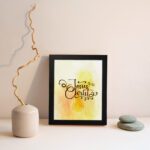 Jesus Christ Bible Wall Art in black script with a yellow cross and watercolor background, framed in black. Perfect Christian home decor. displayed on the wall in a black frame