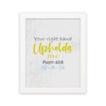 Christian wall art featuring the phrase Your Right Hand Upholds Me in playful fonts with a yellow cursive style and decorative waves. hung on the wall in a white frame