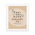 Christian wall art with the phrase "Your Right Hand Upholds Me" Psalm 63:8, featuring bold text and floral accents on a peach background. hung on the wall in a white frame