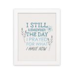 Christian wall art featuring the phrase I Still Remember The Days I Prayed For What I Have Now with floral designs in light blue. hung on the wall in a white frame