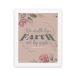 We Walk By Faith Not By Sight Christian Wall Art with pink roses and gray leaves on a soft pink background hung on the wall in a white frame.