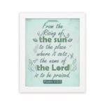 Wall art displaying Psalm 113:3 with elegant cursive font and leafy motifs on a mint green background. hung on the wall in a white frame