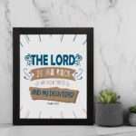 Bible wall art featuring The Lord Is My Rock, My Fortress, and My Deliverer in blue and tan text on a white background with decorative lines. displayed on the wall in a black frame