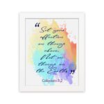 Bible wall art featuring Colossians 3:2 in cursive text on a colorful rainbow background. hung on the wall in a white frame