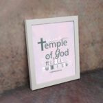 You Are The Temple of God 1 Corinthians 3:16 Christian Wall Art with soft pink background and elegant grey text. displayed on the wall in a white frame