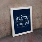 Infidu wall art featuring Bless The Lord O My Soul Psalm 103:1 in gold and white text on a dark blue background with decorative leaves. displayed on the wall in a white frame