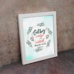 Proverbs 4:7 Bible verse wall art with green leaf wreath and red flowers, perfect for Christian home decor. displayed on the wall in a white frame