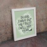 In God I Have Put My Trust, I Will Not Fear Psalm 56:4 bold Christian wall art with green background and brushstroke lettering displayed on the wall in a white frame