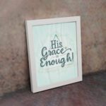 His Grace Is Enough Bible wall art with a mint background and teal script design, surrounded by decorative elements. displayed on the wall in a white frame