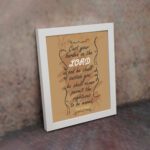 Christian wall art featuring Psalm 55:22, with a warm brown background, dark text, and elegant scrollwork. Perfect for home decor. displayed on the wall in a white frame