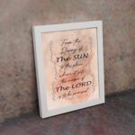 Bible wall art featuring Psalm 113:3 with floral elements and stylish text on a peach background. displayed on the wall in a white frame