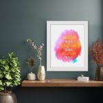 Bible wall art featuring Start With Jesus, Stay With Jesus and End With Jesus in white and orange fonts over a pink, orange, and yellow watercolor background. displayed on the wall in a white frame