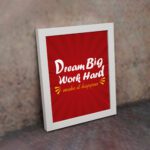 Infidu Dream Big Work Hard Make It Happen wall art with a red background white and yellow text and a white frame on the wall. Inspiring decor for home offices and workspaces.