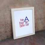 Infidu Take A Small Step Everyday wall art with a gray background navy blue and red text and a white frame on the wall. Inspiring decor for any workspace.