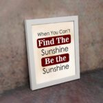 Infidu motivational wall art featuring the quote When You Can't Find the Sunshine Be the Sunshine on a white background with red text and a white frame on the wall. perfect for office decor.