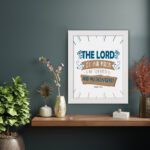 Bible wall art featuring The Lord Is My Rock, My Fortress, and My Deliverer in blue and tan text on a white background with decorative lines. displayed on the wall in a white frame