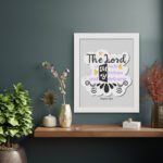 Bible wall art with The Lord Is My Rock, My Fortress, and My Deliverer in colorful pastel text on a light grey background with decorative elements. displayed on the wall in a white frame