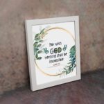 Wall art featuring the quote With God Nothing Shall Be Impossible from Luke 1:37, surrounded by a golden frame and green leaves. displayed on the wall in a white frame