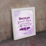 Bible wall art featuring Psalm 63:3 with playful text in purple and pink on a lavender background. displayed on the wall in a white frame