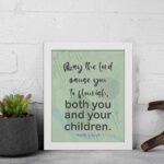 Christian wall art with Psalm 115:14 Bible verse on a light green and gray background with black font and white frame displayed on the wall