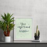 Your Right Hand Upholds Me Psalm 63:8 Christian wall art with dark gray text and light green floral elements on a pale green displayed on the table in a white frame background.