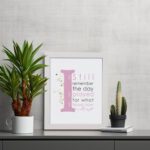 Christian wall art featuring the phrase 'I Still Remember The Days I Prayed For What I Have Now' with pink and gray text and gold flowers. displayed on the table in a white frame