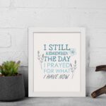 Christian wall art featuring the phrase I Still Remember The Days I Prayed For What I Have Now with floral designs in light blue. displayed on the wall in a white frame