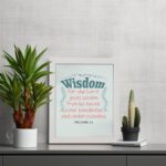 Wisdom Proverbs 2:6 Christian wall art with teal and red text on a mint green background in a black frame. displayed on the table in a white frame