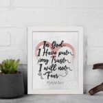 In God I Have Put My Trust, I Will Not Fear Psalm 56:4 Bible Verse Wall Art with pink watercolor arc and black frame. displayed on the wall in a white frame