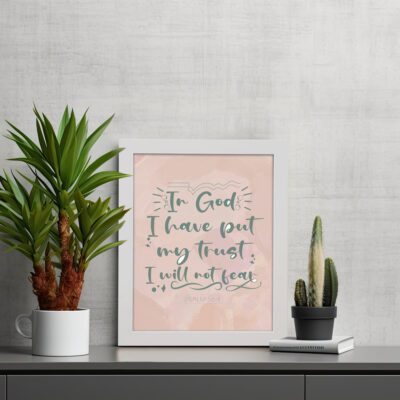 Wall art featuring the quote In God I Have Put My Trust I Will Not Fear from Psalm 56:4 in a bold, playful font. displayed on the table in a white frame