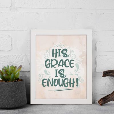 Christian wall art featuring the phrase His Grace Is Enough in teal lettering on a soft pink background with decorative swirls. displayed on the wall in a white frame