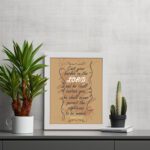 Christian wall art featuring Psalm 55:22, with a warm brown background, dark text, and elegant scrollwork. Perfect for home decor. displayed on the table in a white frame