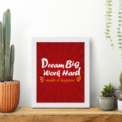 Infidu Dream Big Work Hard Make It Happen wall art with a red background white and yellow text and a white frame on the table. Inspiring decor for home offices and workspaces.