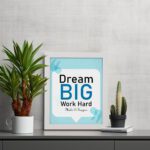 Infidu Dream Big Work Hard Make It Happen wall art with a sky blue and white background and sky blue and black text and white frame displayed on the table. Inspiring decor for home offices and workspaces.