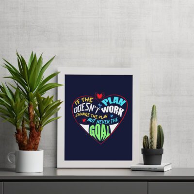 Infidu If The Plan Doesn't Work Change The Plan But Never The Goal wall art with a navy blue background red heart design and white frame on the table. Inspiring decor for home offices and workspaces.