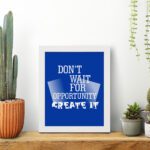 Infidu motivational quotes wall art featuring Don’t Wait For Opportunity, Create It on a blue background and white frame on the table. inspire your workspace