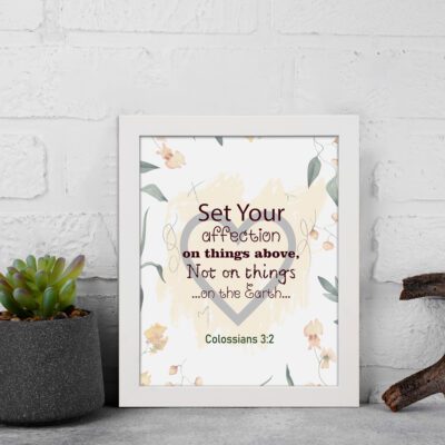 Colossians 3:2 Bible verse wall art with floral design and bold lettering, featuring the words Set Your Affection on Things Above. displayed on the wall in a white frame