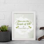 Christian wall art featuring 'You Are The Temple of God His Spirit Dwells in You' from 1 Corinthians 3:16 with green and gray design. displayed on the wall in a white frame