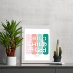 Infidu I Am A Child Of God John 1:12 Christian Wall Art with modern pink and green gradient design on a playful background. displayed on the table in a white frame