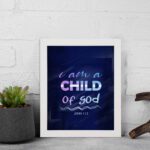 Infidu I Am A Child Of God wall art featuring soft glowing text in pink and blue on a dark blue background. displayed on the wall in a white frame