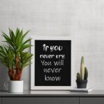 Infidu motivational quotes wall art featuring If You Never Try You Will Never Know on a dark black background and white frame displayed on the table. Perfect for inspiring your workspace.