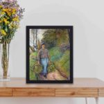 This vintage art print of "Peasant Woman Carrying Two Bundles of Hay" by Camille Pissarro. Painted in 1883,displayed on a table with black frame