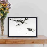 Enhance your decor with this vibrant vintage art print of flying magpies by Watanabe Seitei,displayed on a table