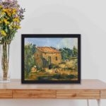 This vintage art print of Paul Cézanne's "Abandoned House near Aix-en-Provence",displayed on a table with black frame