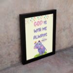 Colorful wall art featuring a cartoon elephant and the text 'God Is With Me Always' inspired by Matthew 28:20. displayed on the wall in a black frame