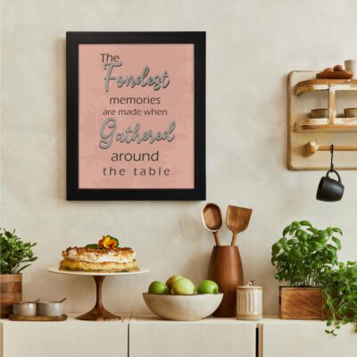 Kitchen wall art with light pink background, floral patterns, and the phrase The Fondest Memories Are Made When Gathered Around The Table. There is a vegetable table, and above it, there is wall art.