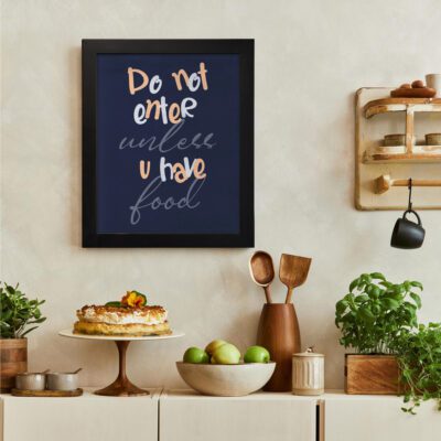 Do Not Enter Unless U Have Food" kitchen wall art with pastel orange and white text on a deep navy-blue background. There is a vegetable table, and above it, there is wall art.