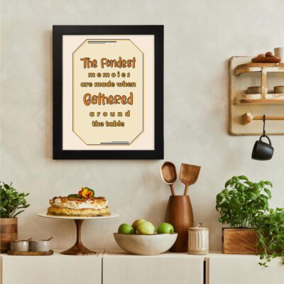 Beige kitchen wall art with the text "The fondest memories are made when gathered around the table" in a bold brown and orange decorative font. There is a vegetable table, and above it, there is wall art.