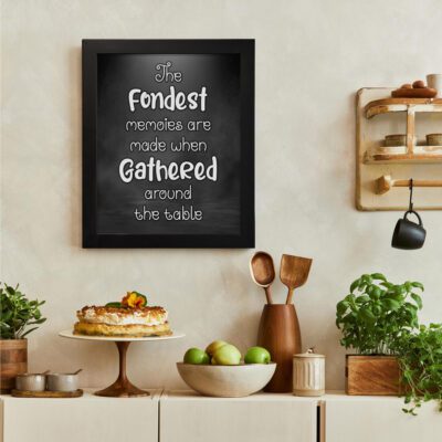 Black kitchen wall art with the quote "The Fondest Memories Are Made When Gathered Around The Table" in bold white font. There is a vegetable table, and above it, there is wall art.