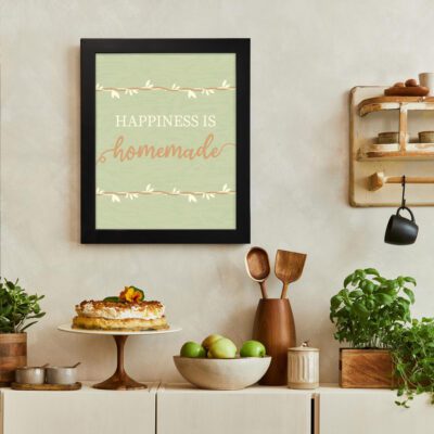 Happiness Is Homemade Kitchen Wall Art with green background, white decorative branches, and white-orange text. There is a vegetable table, and above it, there is wall art.